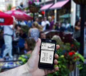 person holding phone in front of crowded outdoor restaurant