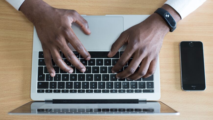Black man types on a laptop