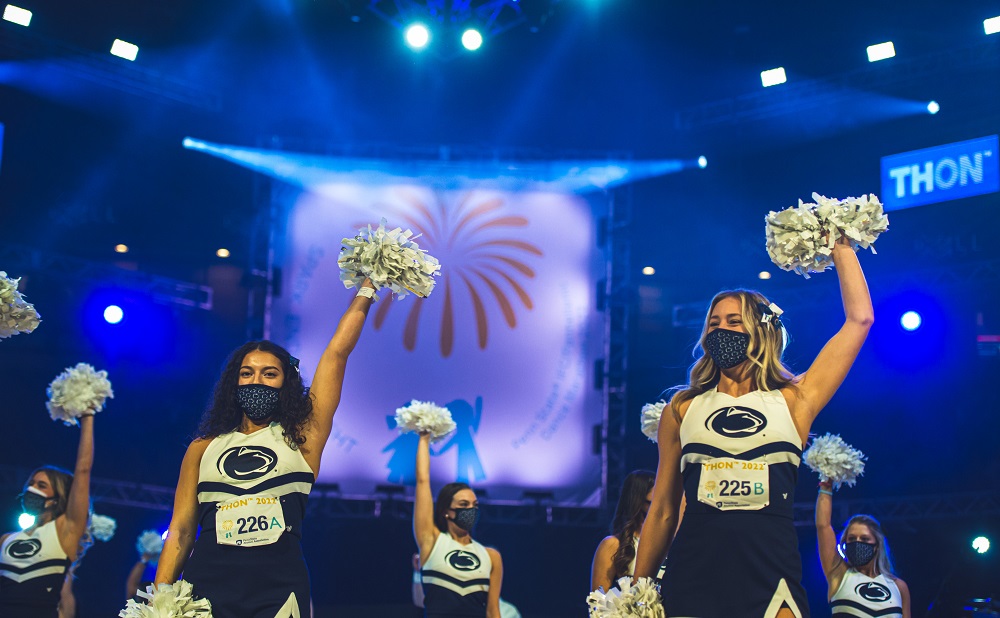 Penn State cheerleaders with raised arms holding pom poms at THON