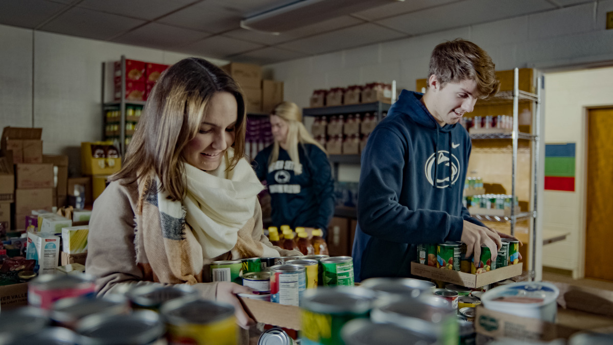Students - some wearing Penn State apparel - sorting canned goods at a food pantry