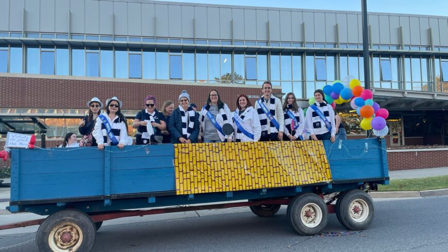 Students wearing Penn State gear riding on a float in the Homecoming parade