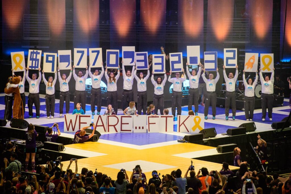 Group of students on THON floor holding cards with numbers signfiying the total amount of money raised