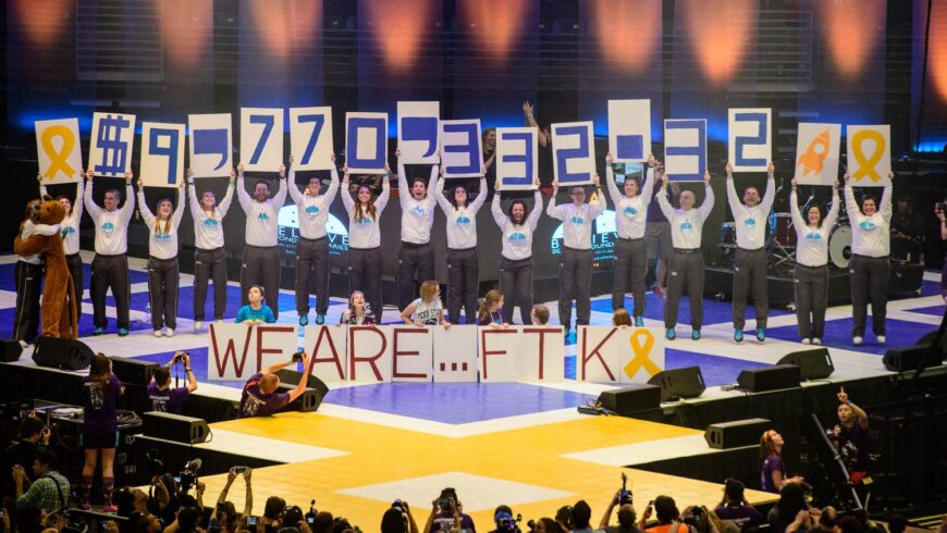Group of students on THON floor holding cards with numbers signfiying the total amount of money raised