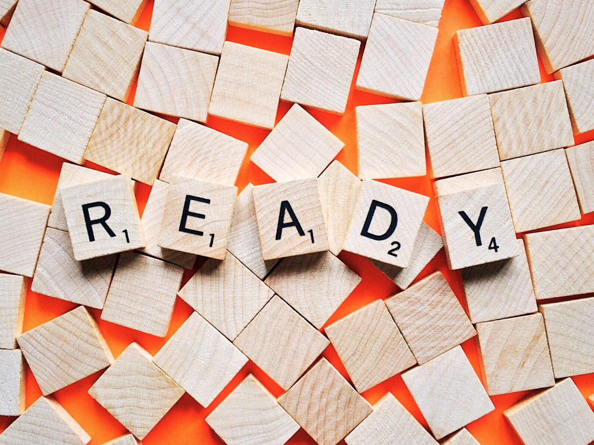 Group of small wooden tiles, most of which are blank but five have letters spelling out the word "ready"