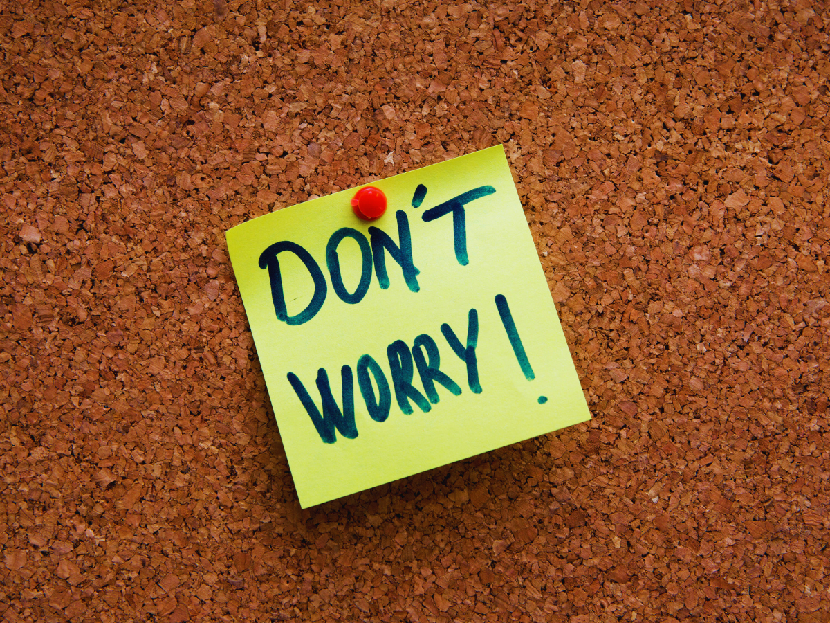 "Don't worry!" written on a post-it note attached to a cork board