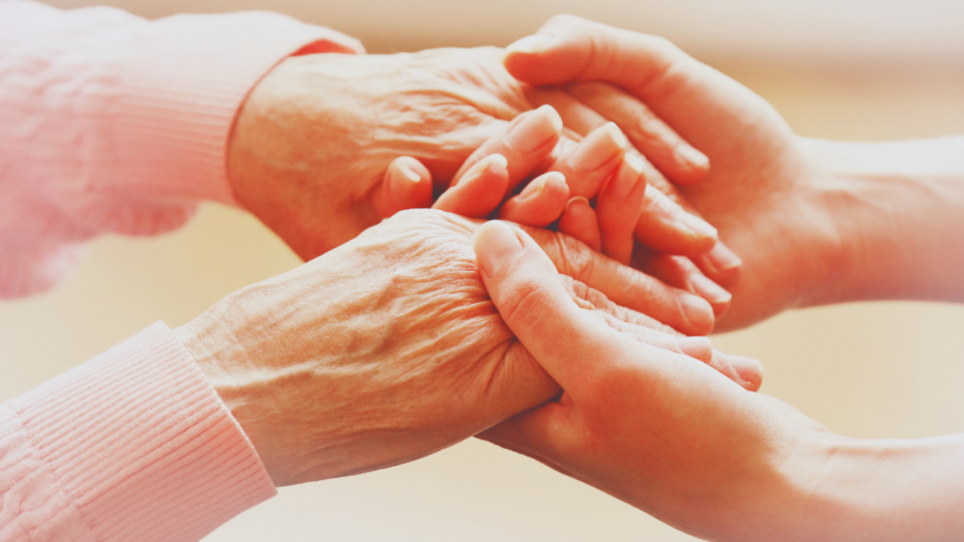 One pair of younger-looking hands holding hands that appear to be those of an older person