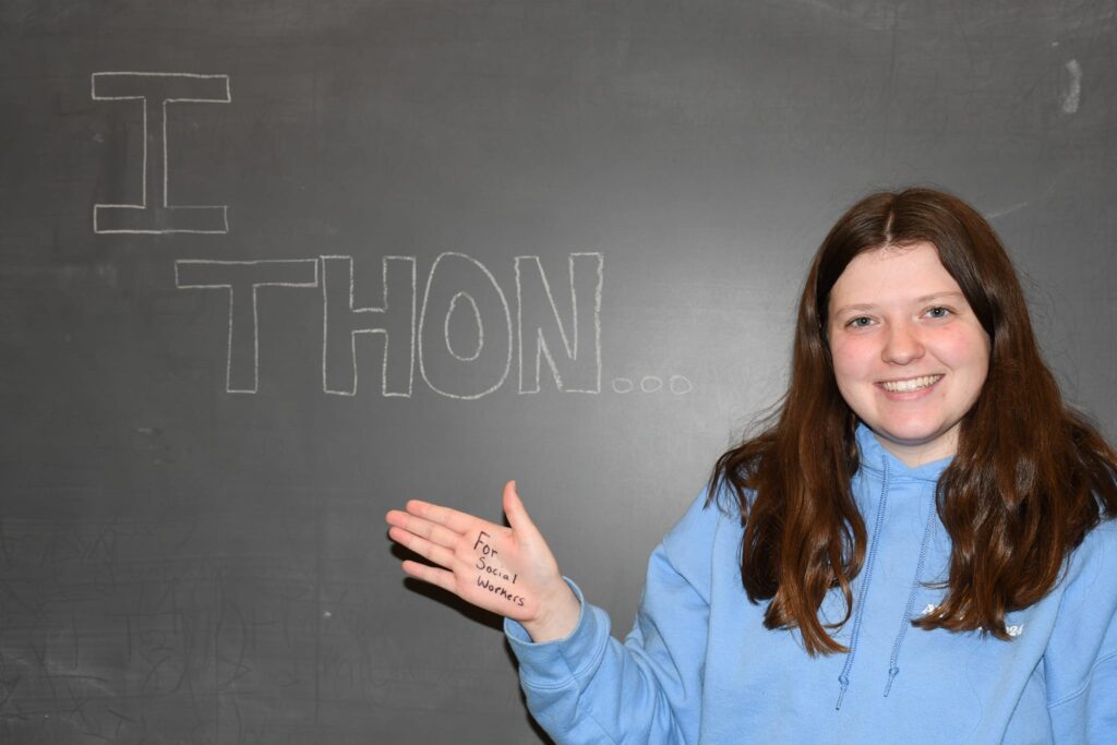 Smiling woman standing in front of a wall with the word THON written on it