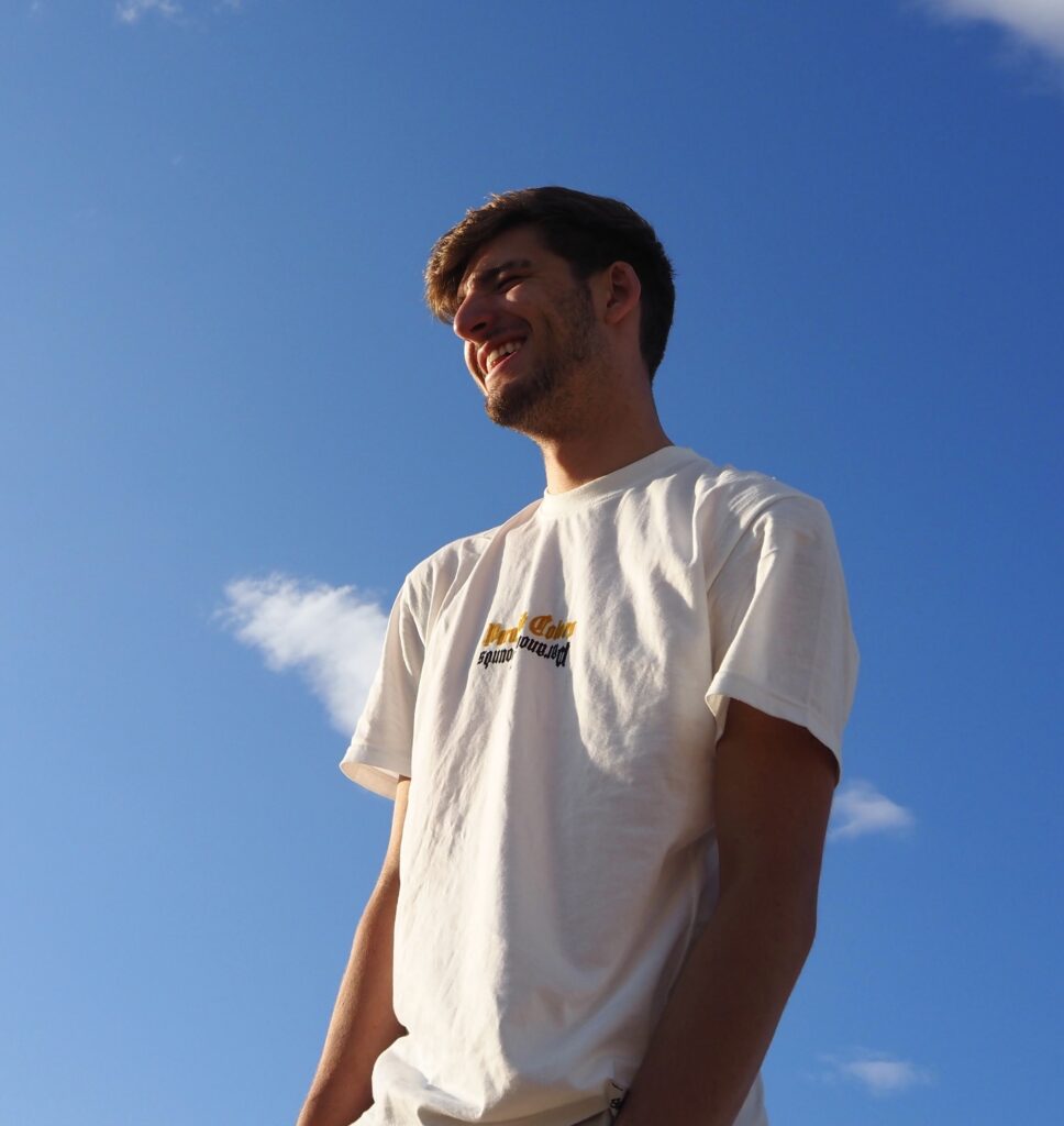 Man with dark hair standing in front of a bright blue sky